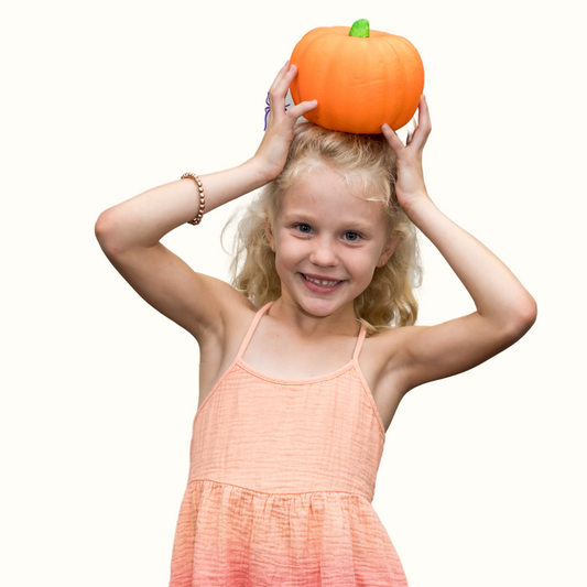 Elementary student holding a pumpkin on their head